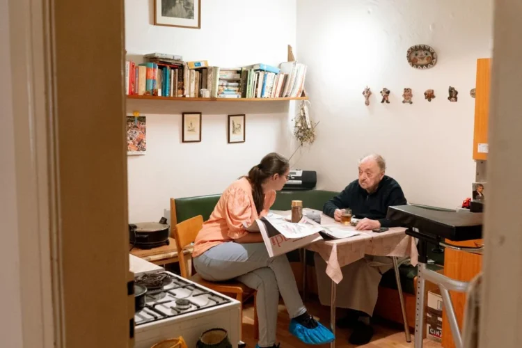 Aide à domicile échangeant avec une personne âgée dans sa cuisine