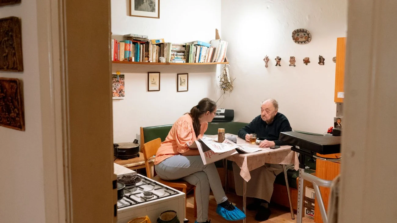 Aide à domicile échangeant avec une personne âgée dans sa cuisine